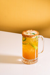 Michelada refrescante servida en un vaso transparente, con hielo y rodaja de lima. Imagen vibrante...