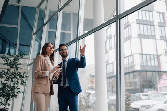 Businesspeople planning strategy, pointing at new office building window