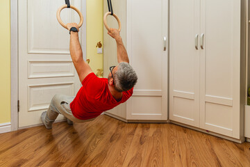 Man performs fitness exercise using rings at home