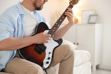 Man playing electric guitar at home, closeup