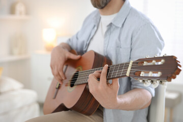 Man playing guitar at home, focus on hand