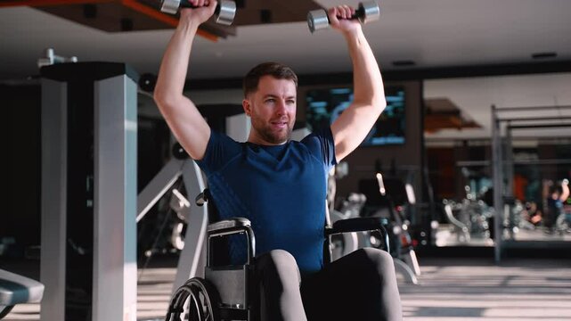Young man in wheelchair lifting dumbbells at gym