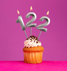 Birthday candle number 122 with cupcake on violet background