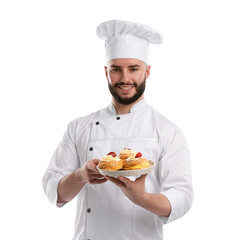 Happy confectioner in uniform holding delicious profiteroles with strawberries on white background