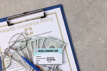 Medical insurance card, policy, money, glasses and pen on grey table, top view