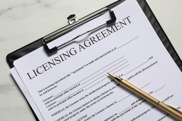 Licensing agreement document and pen on white marble table, top view