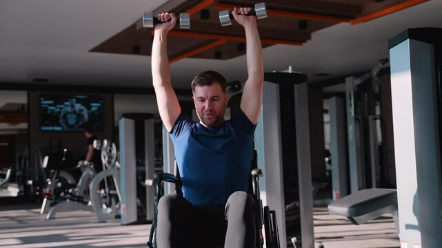 Smiling man in wheelchair lifting dumbbells at gym, demonstrating motivation, strength training