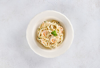 Spaghetti with shrimps, parsley and cream sauce on a white background. Top view. Italian food.