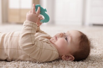 Cute little baby with rattle toy on floor at home
