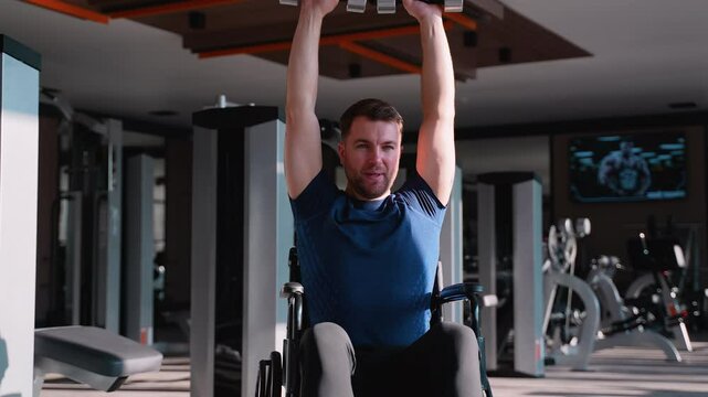 Man in wheelchair lifting dumbbells overhead