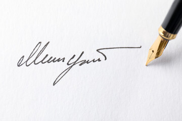 Fountain pen leaving signature on paper, closeup