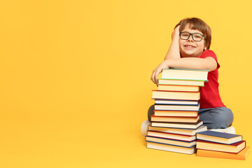 Boy with many different books on orange background. Space for text