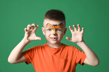 Cute boy with tiger face painting on green background