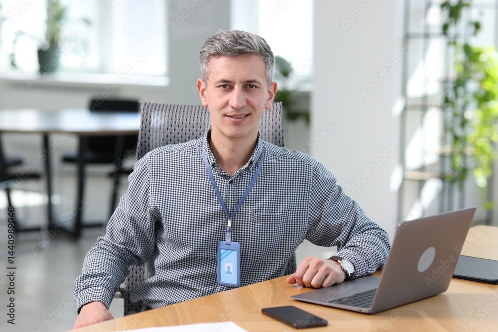 Poster smiling engineer working with laptop at table in office