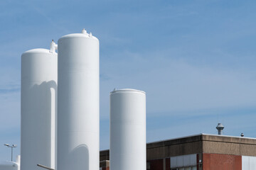 Large white storage tanks against clear blue sky at industrial facility