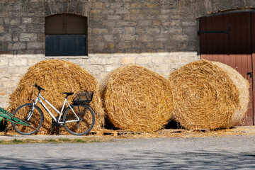 Bicycle parked next to straw bales against stone wall backdrop