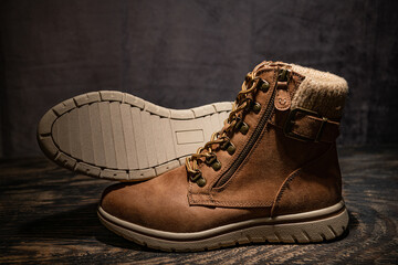 Brown women's leather boots with high lacing on a dark wood floor. Demi seasonal boots with zipper locks.