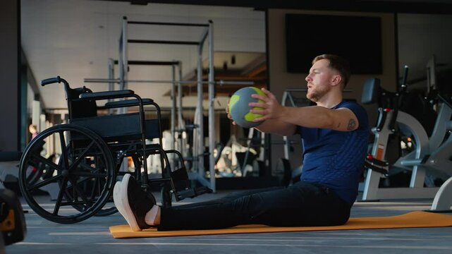 Man with disability doing core workout with medicine ball on mat