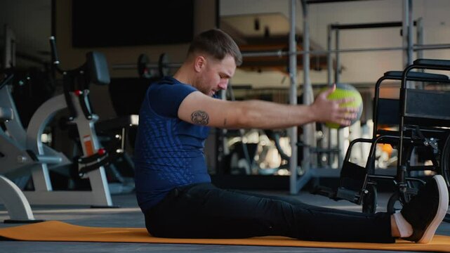 Man with disability training abs with medicine ball on yoga mat