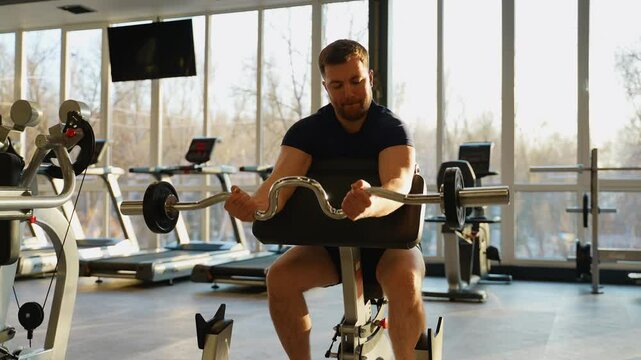 Man training biceps with barbell in gym