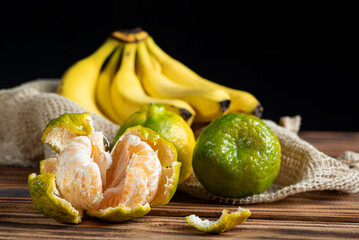 Oranges and Bananas, oranges and bananas positioned on a rustic wooden surface and dark background, selective focus.
