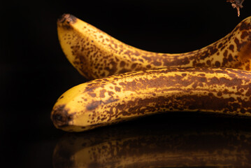 Ripe banana, almost overripe bananas on a black reflective surface and dark background, selective focus. © Milton Buzon