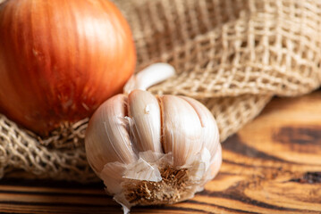 Garlic and onion, a head of garlic and an onion on a rustic wooden surface and dark background, selective focus.
