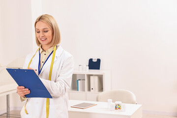 Weight loss. Happy nutritionist with clipboard in clinic, space for text