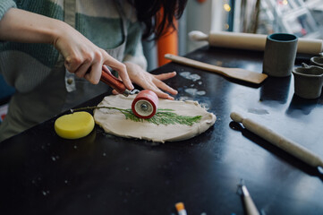 Ceramist imprinting botanical design into clay using a rolling pin