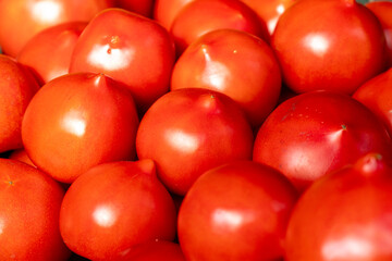 Vibrant red tomatoes are neatly arranged at a market stall, inviting customers to enjoy fresh and healthy produce