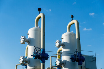 Two large gas processing units stand tall at an industrial site, surrounded by a bright blue sky during the day