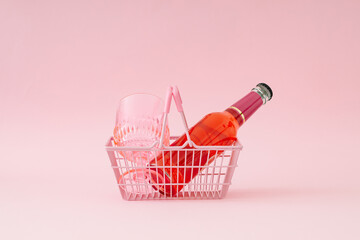 Watermelon drink and pink drinking glass in pink shopping basket on pastel pink background. Minimal refreshing summer drink concept. Trendy summertime party idea.