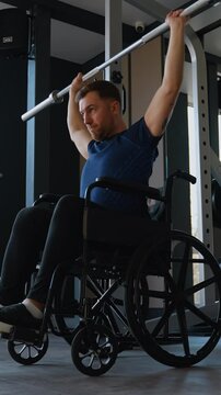 Man in wheelchair lifting barbell at gym