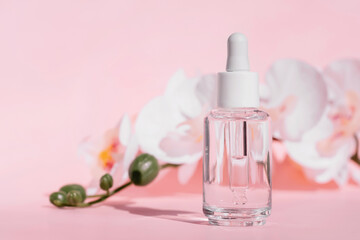Transparent serum glass dropper bottle with white cap, set against soft pink flower background, clean and minimalistic beauty product design
