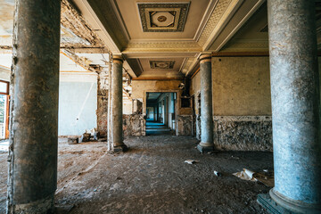 Decaying neoclassical hall with majestic marble columns and ornate ceiling in abandoned historic building.Soviet architecture, luxury ruins.