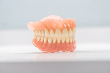 Close-up of a dental prosthetic model with artificial teeth and gums on a wooden surface. Ideal for dental care imagery