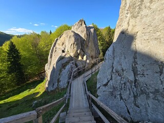 Tustan Rocks in Spring, Carpathian Mountains, Ukraine. Scenic view of Tustan rock formations surrounded by spring forest under a blue sky. Historical and natural landmark in the Carpathian Mountains