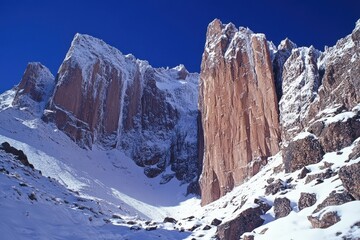 Skier Gliding on Snowy Andean Peaks with Rocky Foreground and Clear Blue Sky
