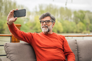 senior man sit on the terrace use mobile phone talk on video call