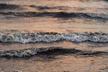 Close-up of gentle waves rolling across the surface of the sea at dusk. The soft lighting reflects off the water, creating peaceful and serene atmosphere