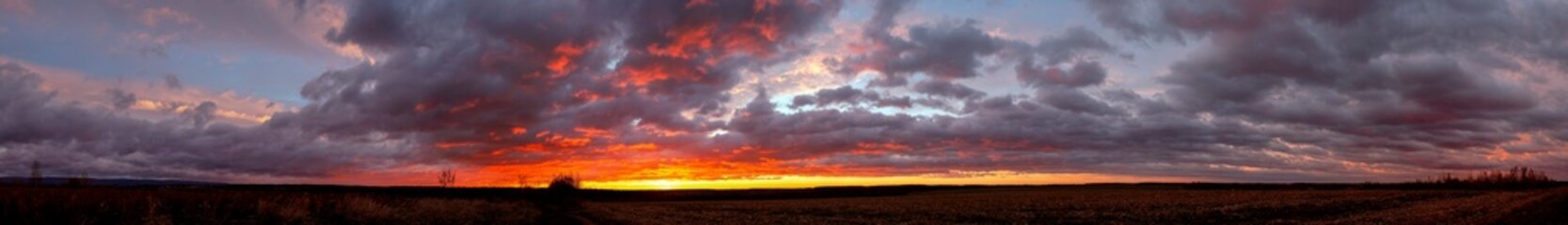 A stunningly beautiful sunset sky and colorful clouds over a field of mown corn.