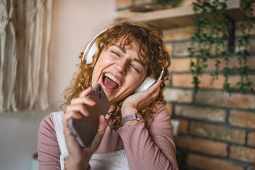cheerful woman use mobile phone and headphones listen music and dance