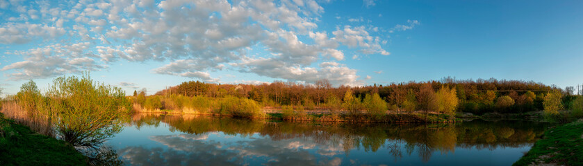Panorama of forest lakes in spring, young leaves and freshly blossomed buds of trees and shrubs