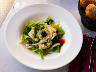 Traditional Catalan esqueixada with salt cod, onion, greens and olives. Spanish cuisine..
