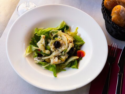 Traditional Catalan esqueixada with salt cod, onion, greens and olives. Spanish cuisine..