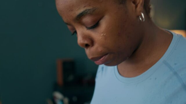 Tilting slowmo closeup of sweaty young Black plus-sized woman drinking water from sports bottle after treadmill workout at home
