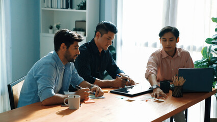 Fototapeta premium Group of diverse people sharing idea while writing at sticky notes. Professional smart business team brainstorming idea and planning strategy for startup project while wear casual outfit. Convocation.