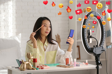 Female Asian beauty blogger with eyeshadows recording video at home