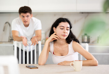 Young guy screams during family quarrel with young woman in kitchen