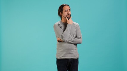 Pensive man deep in thoughts, doing ruminating hand gesturing, isolated over studio background....